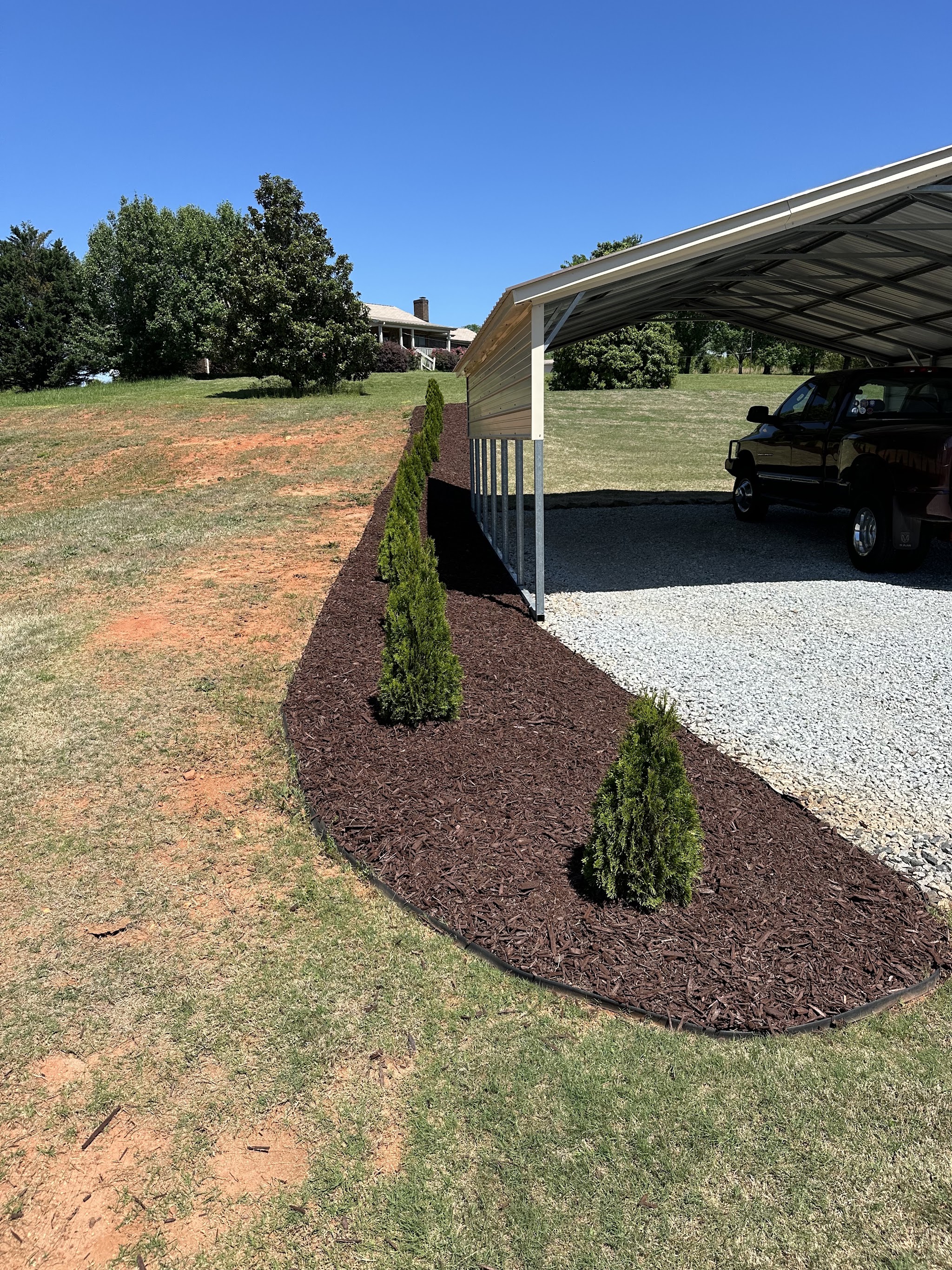 Fresh mulch with young shrubs along a carport